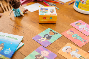 Wooden table that has all the pieces from Little Patakha product Different Fits Mix and Match Game spread out and put together. Parts of Planet Pathrado Konkani Language Learning Book and Mini Ava Cultural Doll are also visible