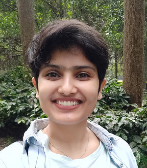 Illustrator at Little Patakha Yogita Chawdhary wearing a button down shirt with a t shirt and smiling surrounded by trees