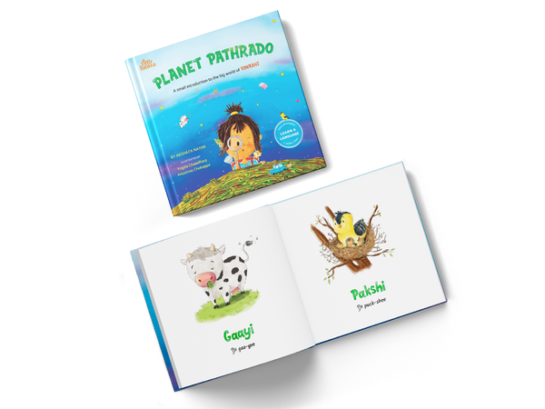 Little Patakha product Planet Pathrado Konkani Language Learning Book picture showing the cover of the closed book and an open book showing what the inside pages look like with the written phonetics and two illustrations of a cow and bird